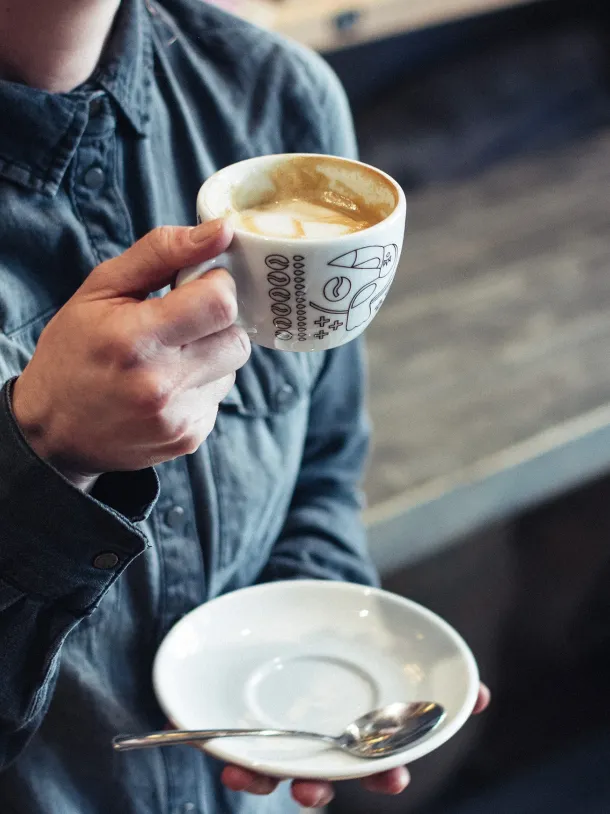 Chico con un café en la mano disfrutando de el 